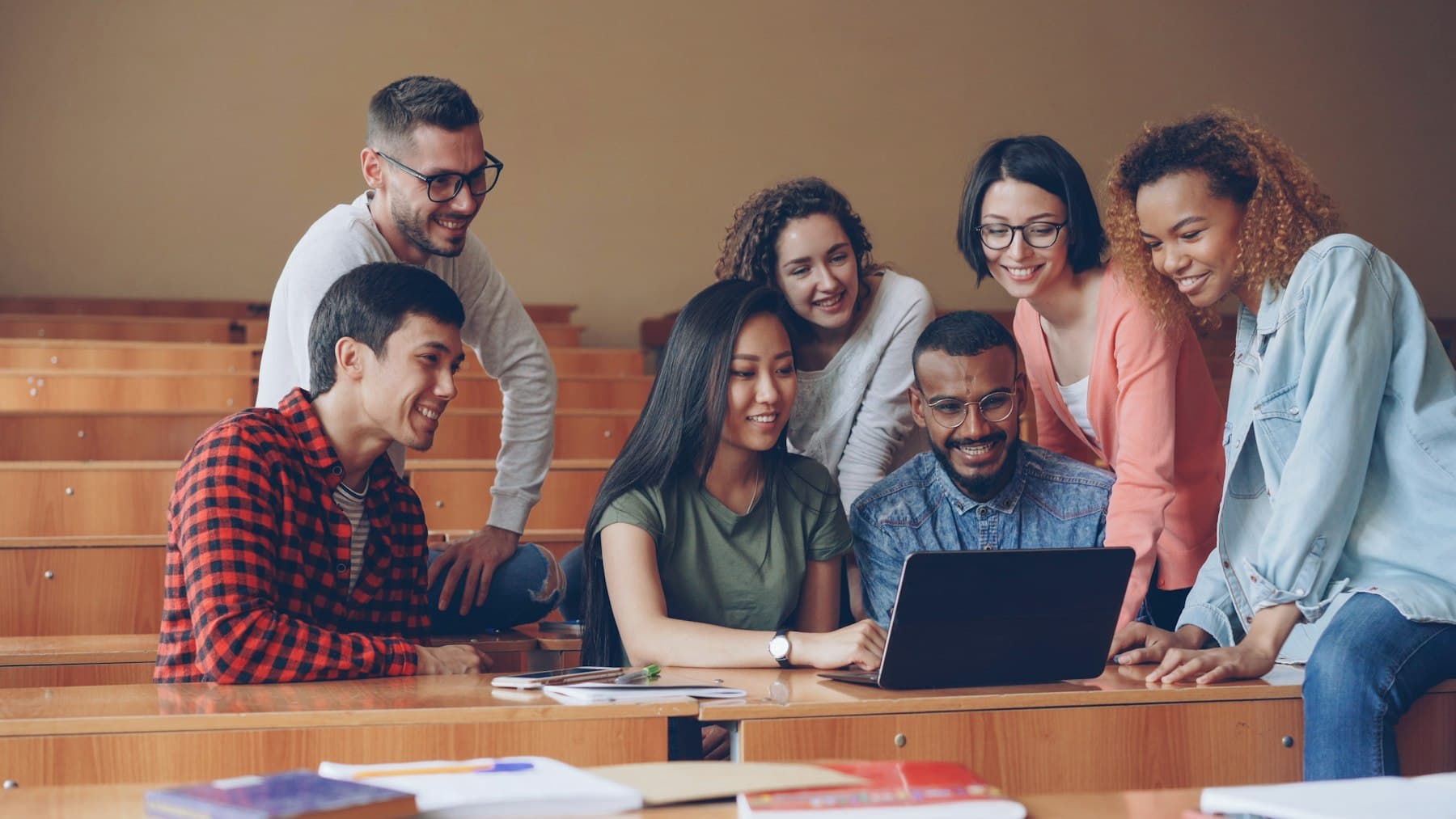 A diverse group of students working together around a laptop