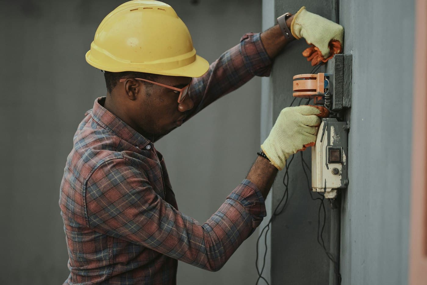 An electrician in a yellow hard hat at work